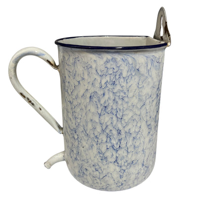 A vintage enamel pot with a blue and white marbled pattern, featuring a white handle with distressed detailing, a dark blue rim, and a silver metal loop handle on top.