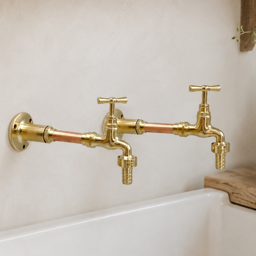 Gold faucets on a white sink with a wooden shelf in the background