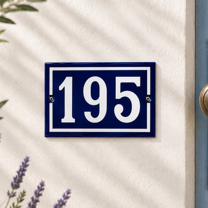 Blue and white house number '195' sign on a white wall with lavender flowers.