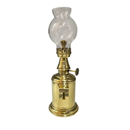 Vintage brass oil lamp with clear glass shade on a white background