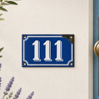 Blue house number plate with '111' on a white wall.