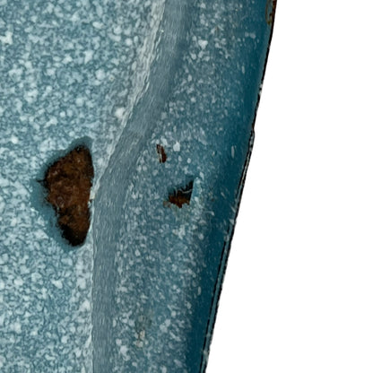 Close-up of wear and tear on a blue metal planter on a white background