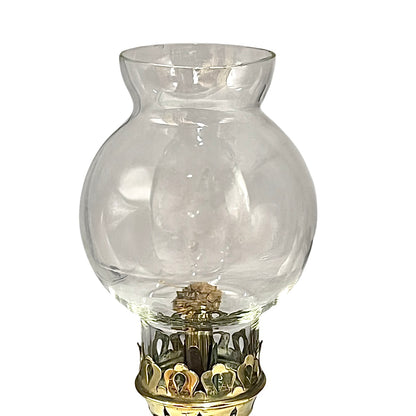 Clear glass oil lamp with decorative base on a white background