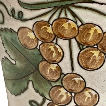 Close-up of a ceramic bucket with grapes and green leaves