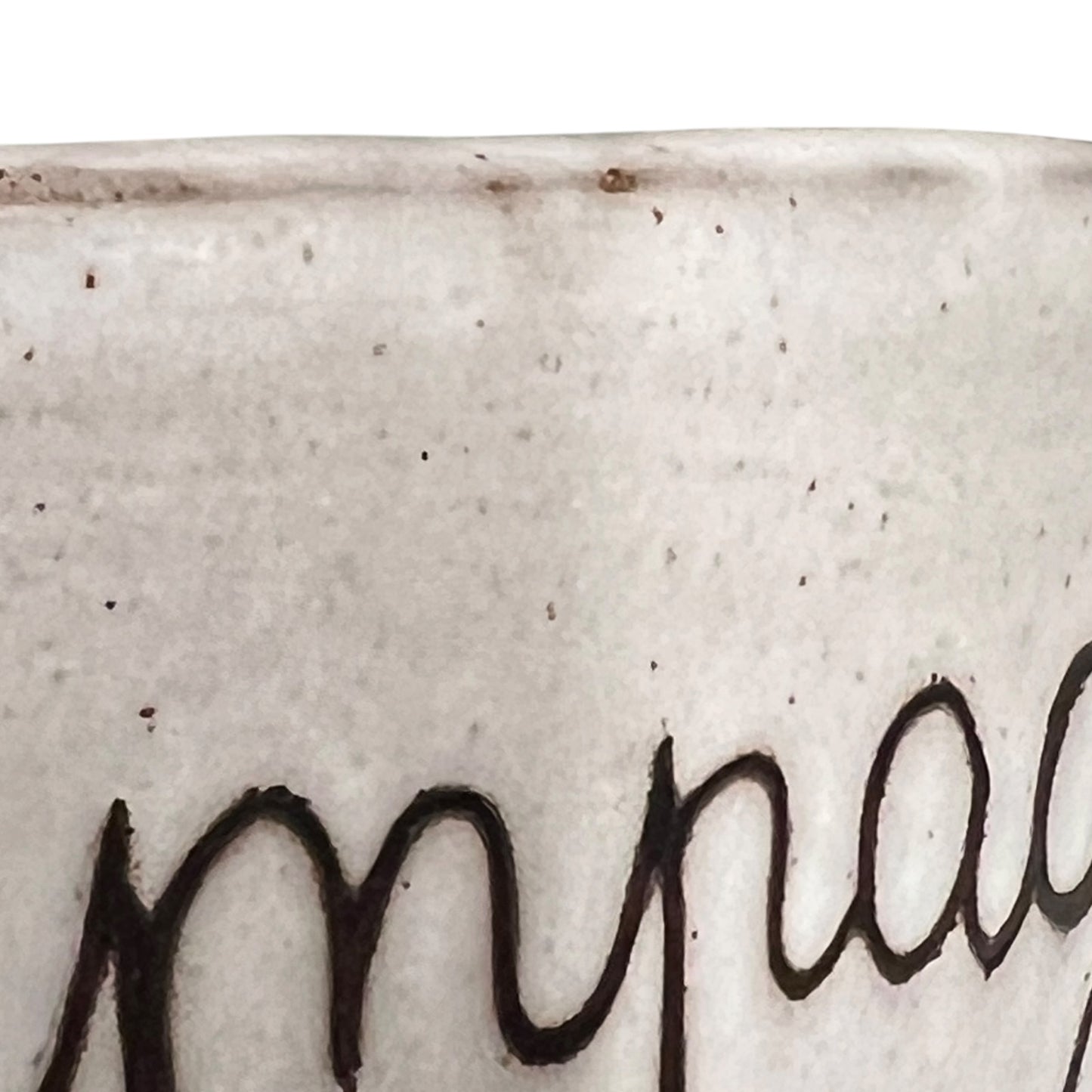 Close-up of a textured ceramic surface with a signature in black.
