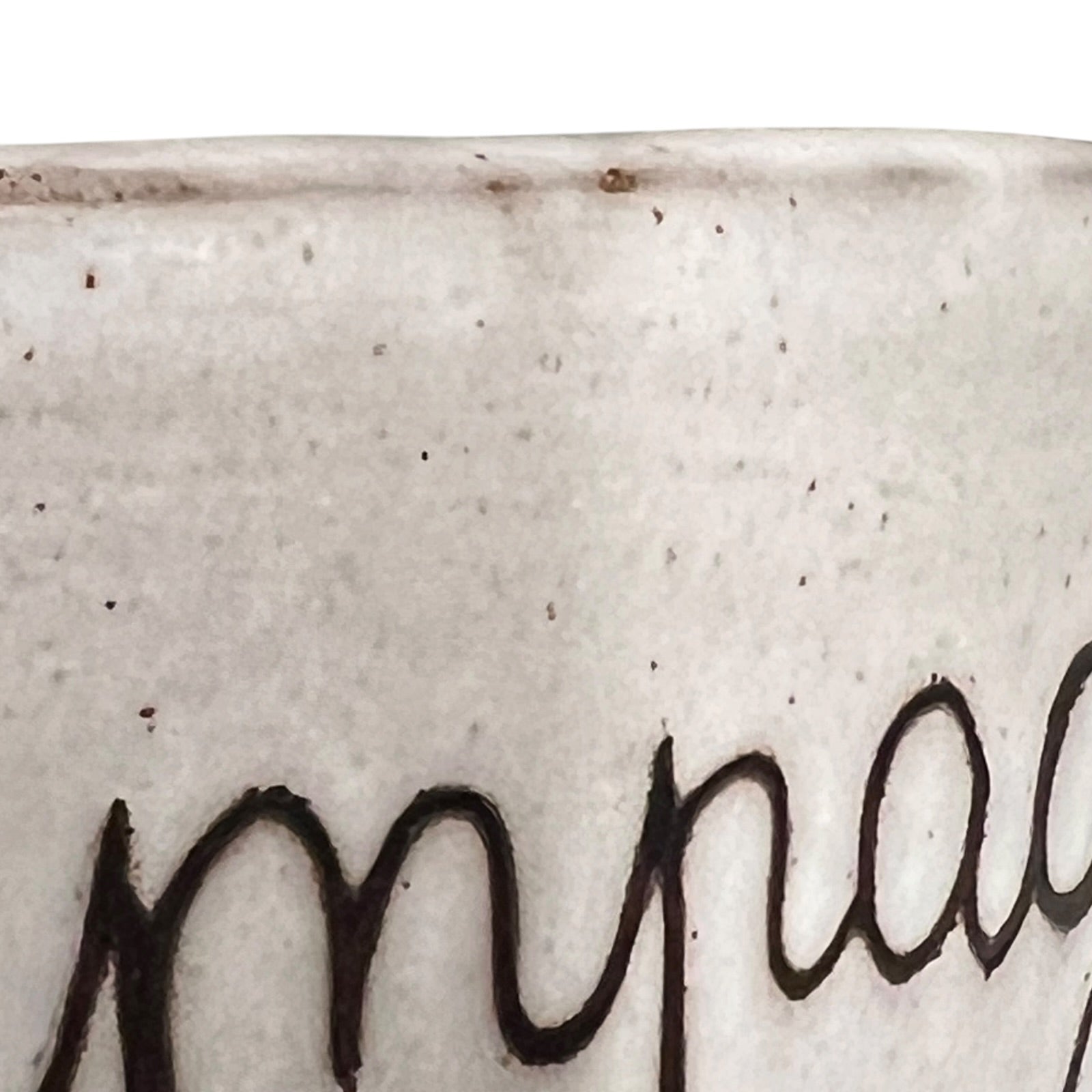 Close-up of a textured ceramic surface with a signature in black.