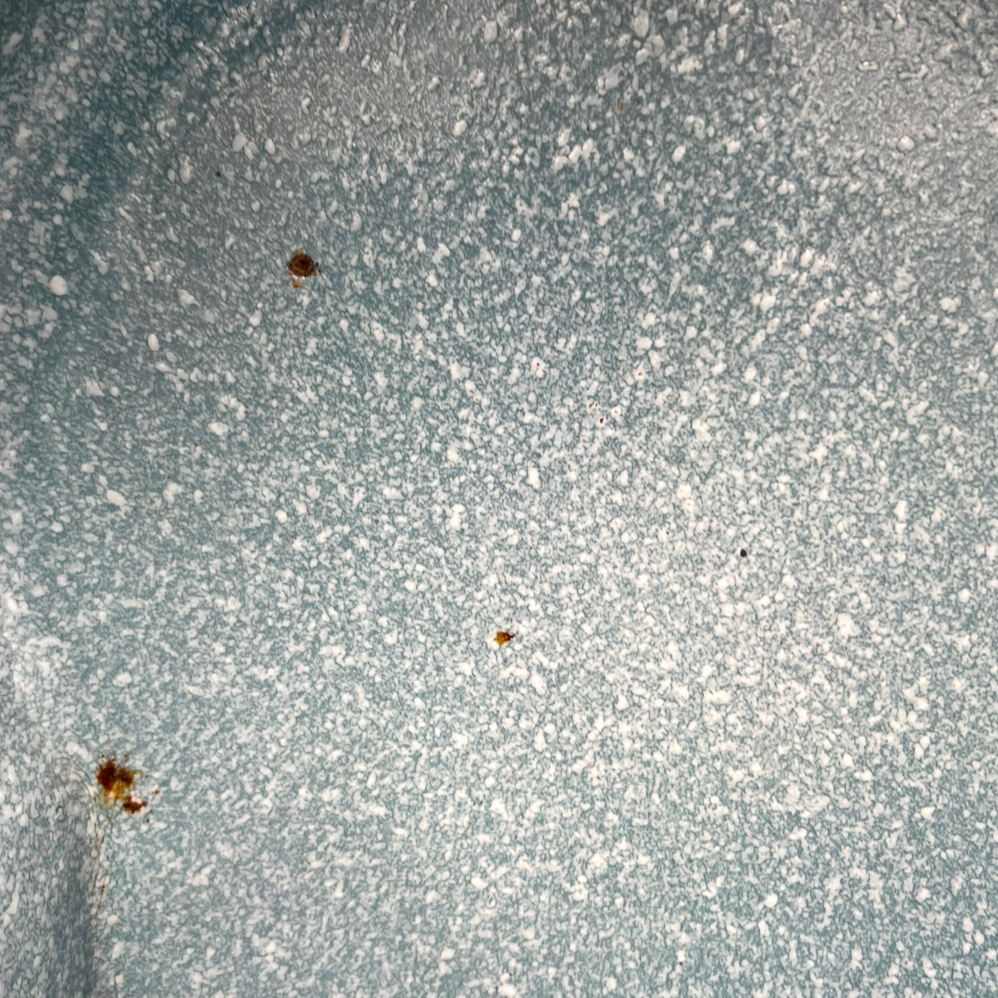 Close-up of wear and tear on a blue metal planter on a white background