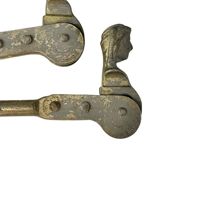 Close up of two rusty metal Belgian ladies shutter dogs on a white background