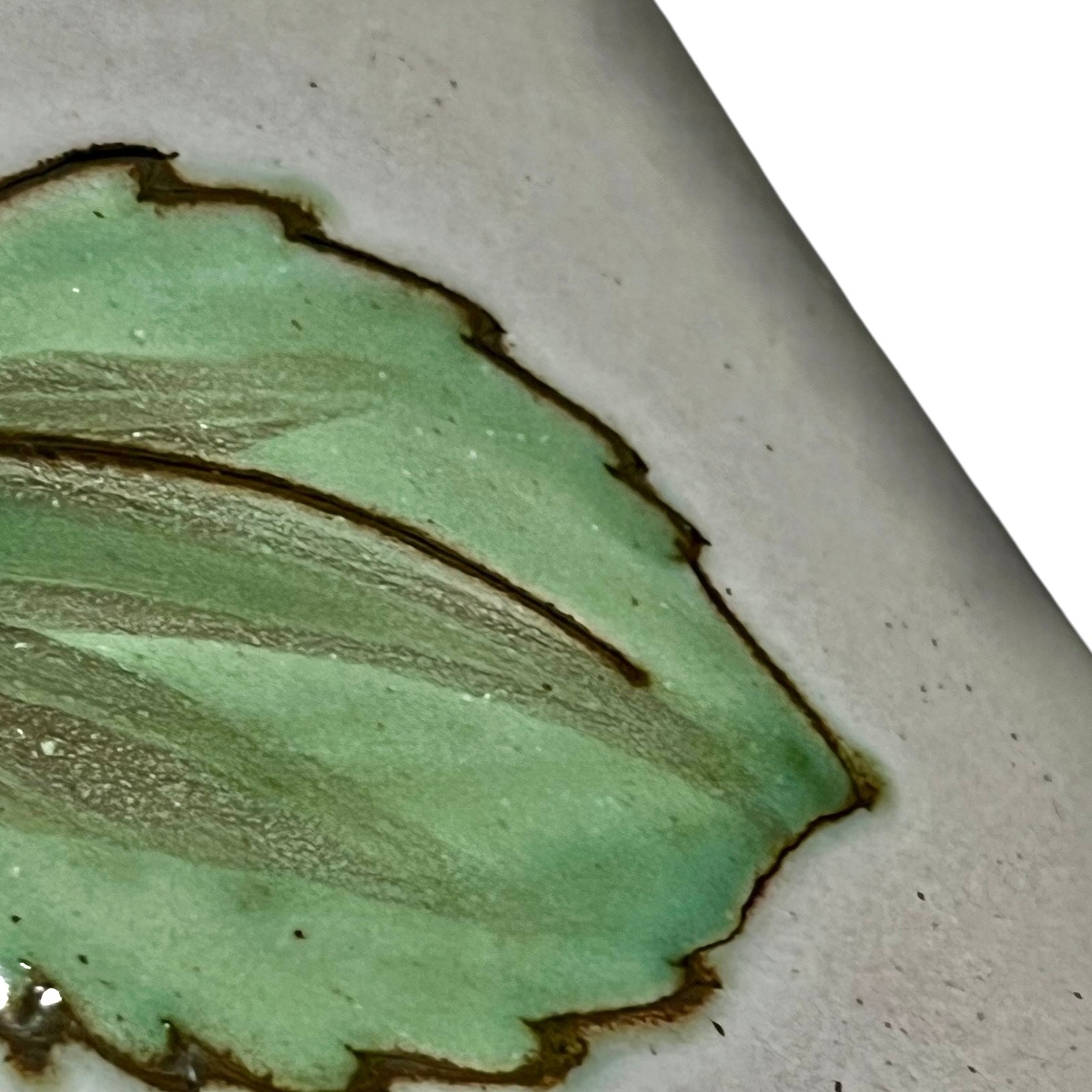 Close-up of a ceramic pot with green glaze and brown rim