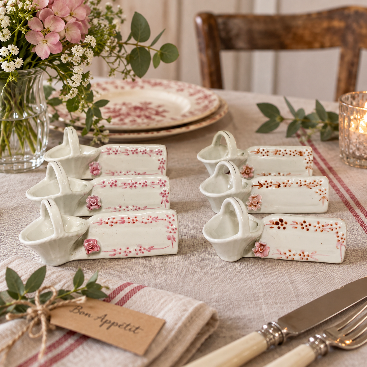 Vintage French ceramic cutlery rests and place settings, set of six with small basket holders and pink floral decoration, styled on a rustic French country dining table.