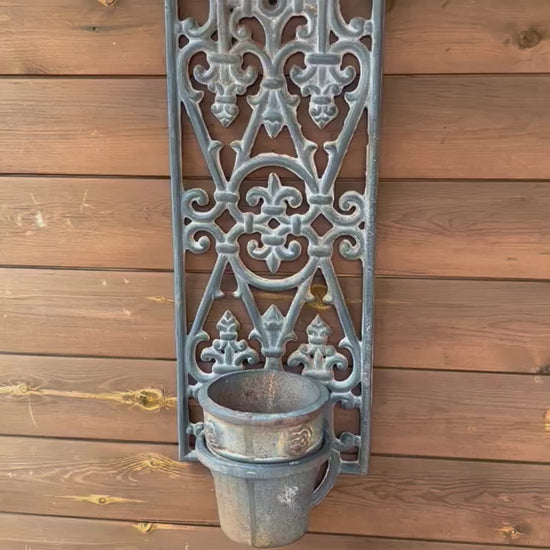 Video of a decorative cast iron French vintage metal wall art with a planter pot on garden shed