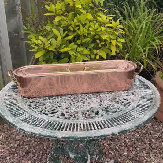 Video of a copper French fish poaching pan with lid on a table in a garden