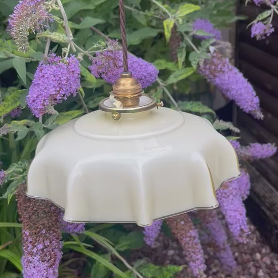 video of a French pale coloured milk glass ceiling pendant light with a green garden and foliage in the background 