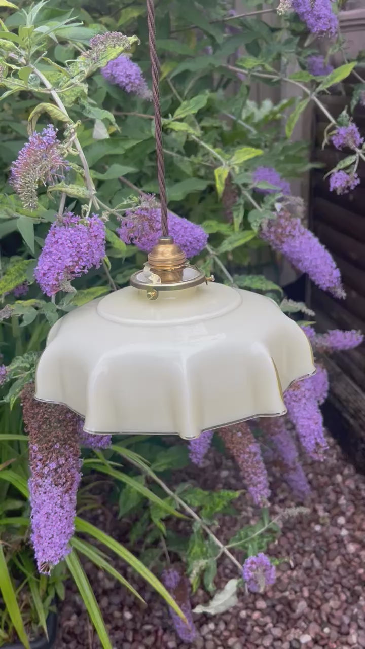 video of a French pale coloured milk glass ceiling pendant light with a green garden and foliage in the background 