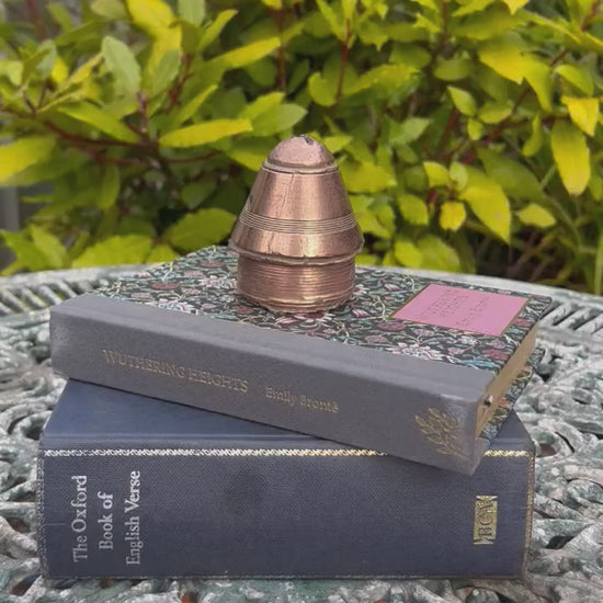 video of a ww1 brass fuse in a garden on top of 2 books