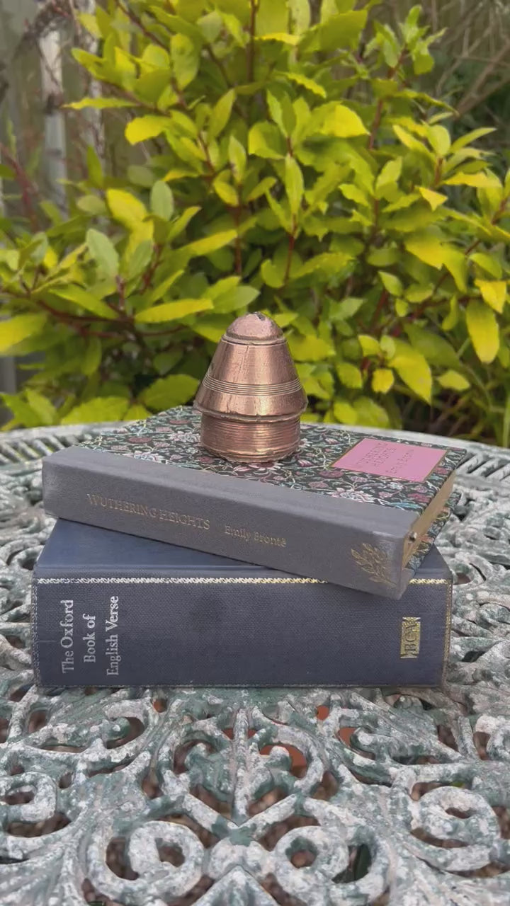 video of a ww1 brass fuse in a garden on top of 2 books