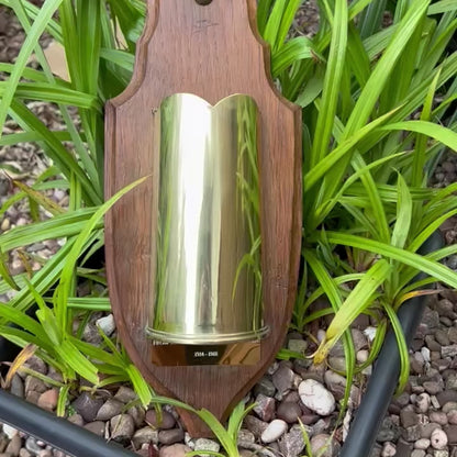 video of a ww1 trench art vase on a wooden plaque in a garden setting 
