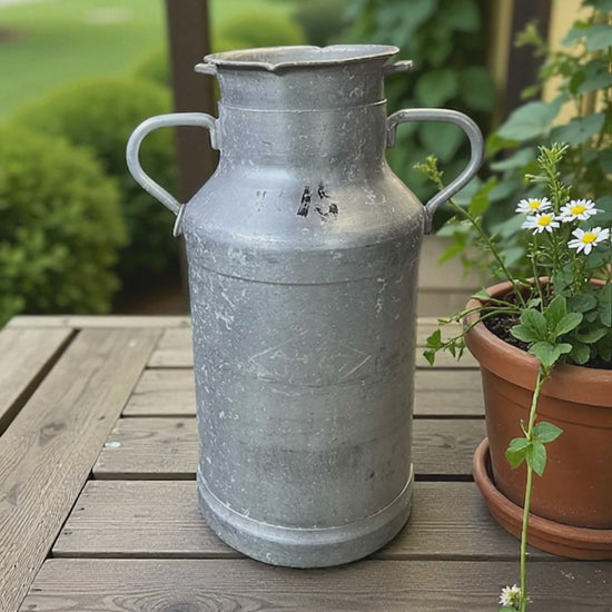 video of French vintage milk churn on a wooden rustic porch next to a plant pot