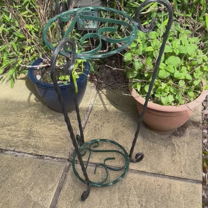 A video of a French vintage wrought iron plant stand in a garden setting with a planter full of lavender. A rustic aesthetic ideal for a cottage garden