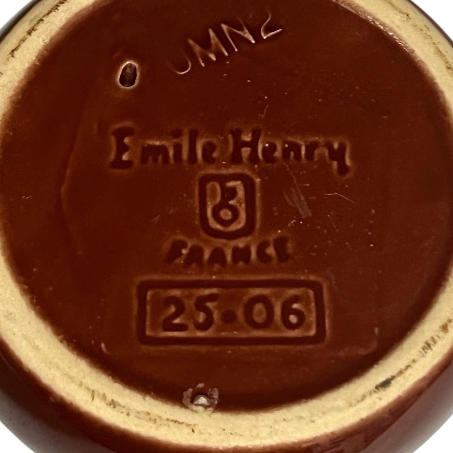 Reverse of a  French brown and cream ceramic escargots dish or plate with the Emile Henry makers stamp on a white background 