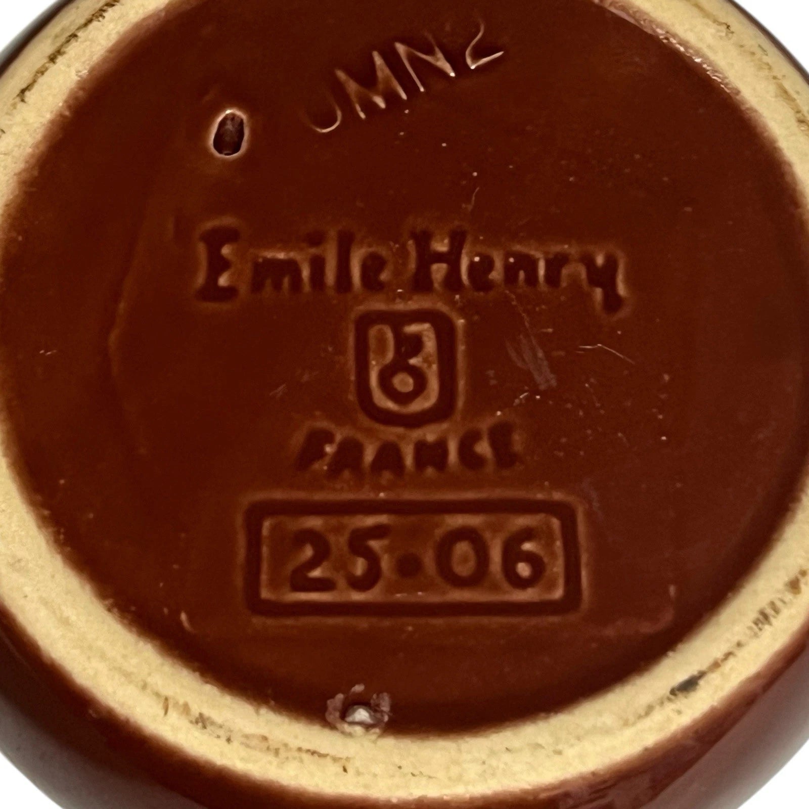 Reverse of a  French brown and cream ceramic escargots dish or plate with the Emile Henry makers stamp on a white background 