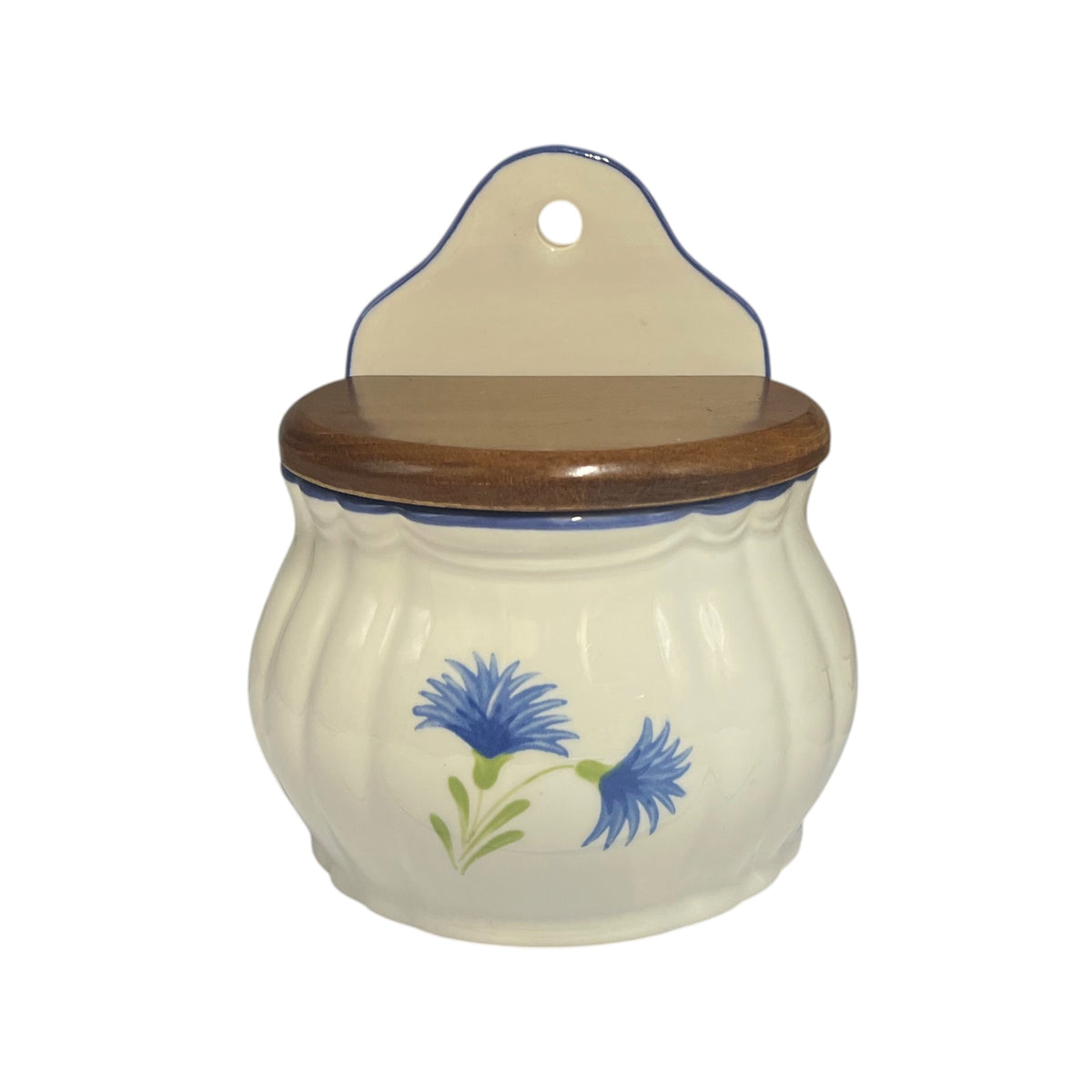 A ceramic jar with a ribbed cream-colored body, a dark brown wooden lid, and a matching hanging tab on top. The jar is decorated with a blue and green cornflower design on the front.