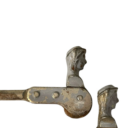 Close up of two rusty metal Belgian ladies shutter dogs on a white background