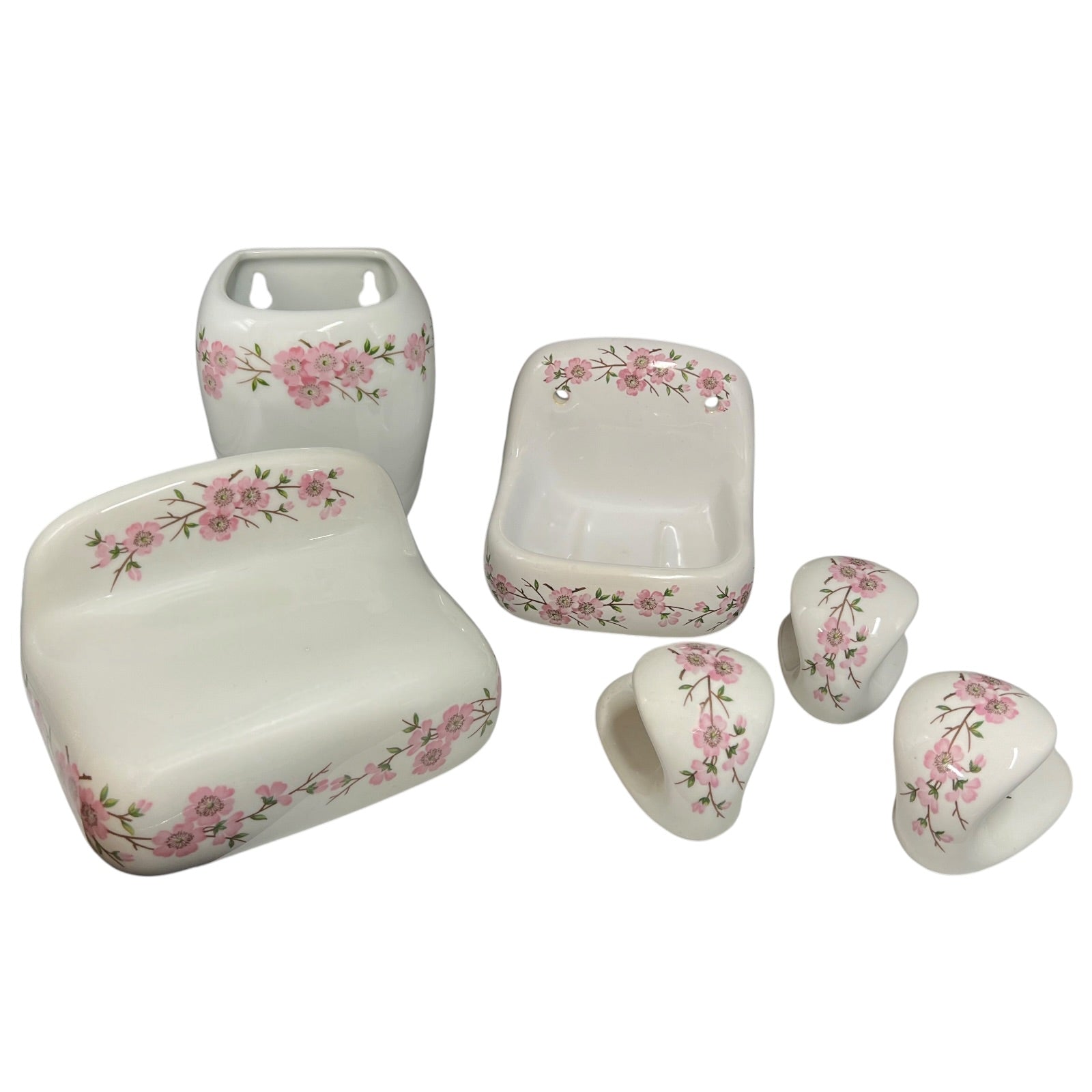 A six-piece white ceramic bathroom vanity set with a pink floral border pattern, including a sink tray, soap dish, pedestal sink, and three cabinet knobs, shown on a white background.