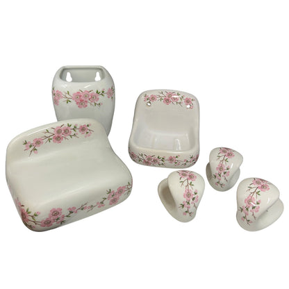 A six-piece white ceramic bathroom vanity set with a pink floral border pattern, including a sink tray, soap dish, pedestal sink, and three cabinet knobs, shown on a white background.