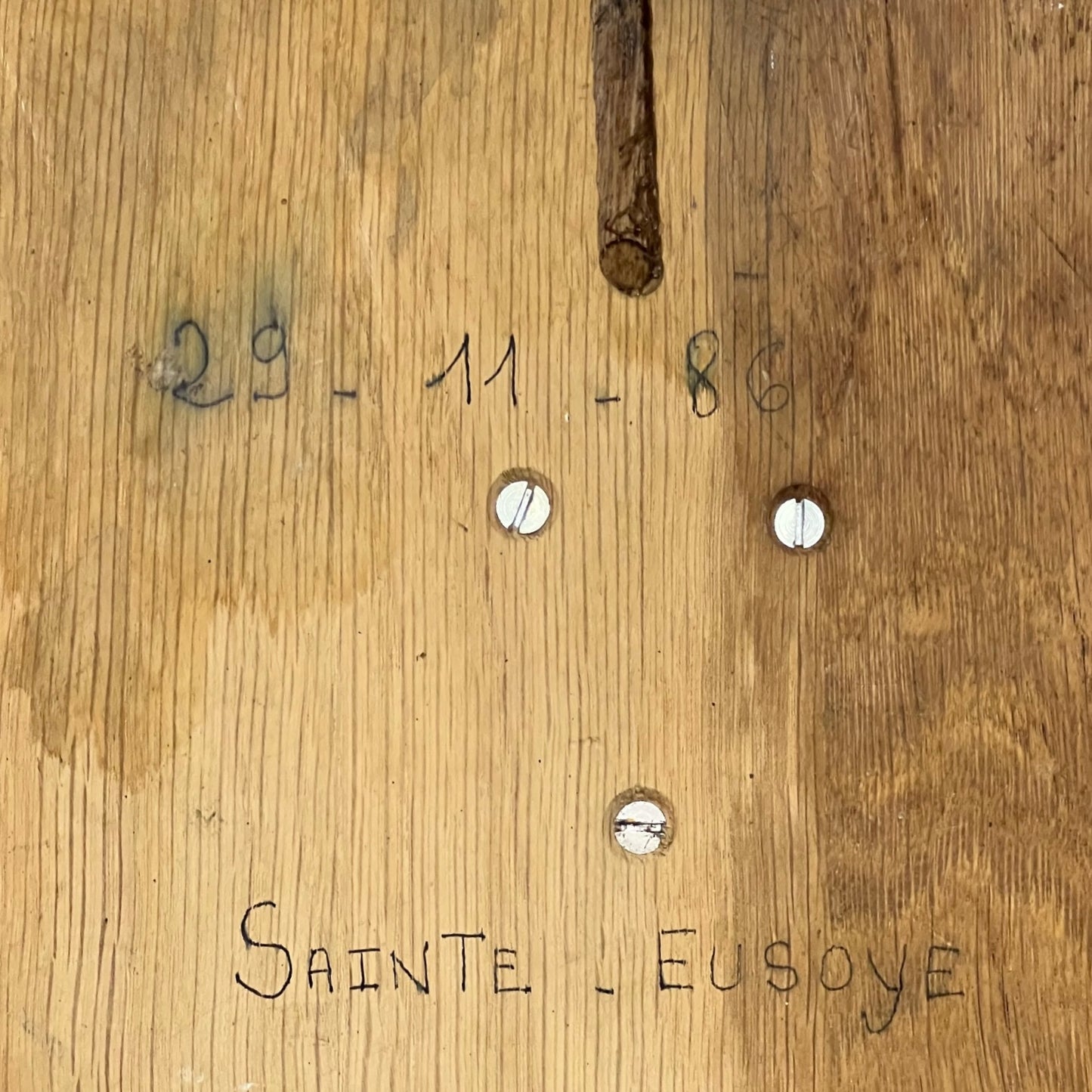 Wooden surface with engraved text and holes, featuring the name 'Sainte Eusoye'.