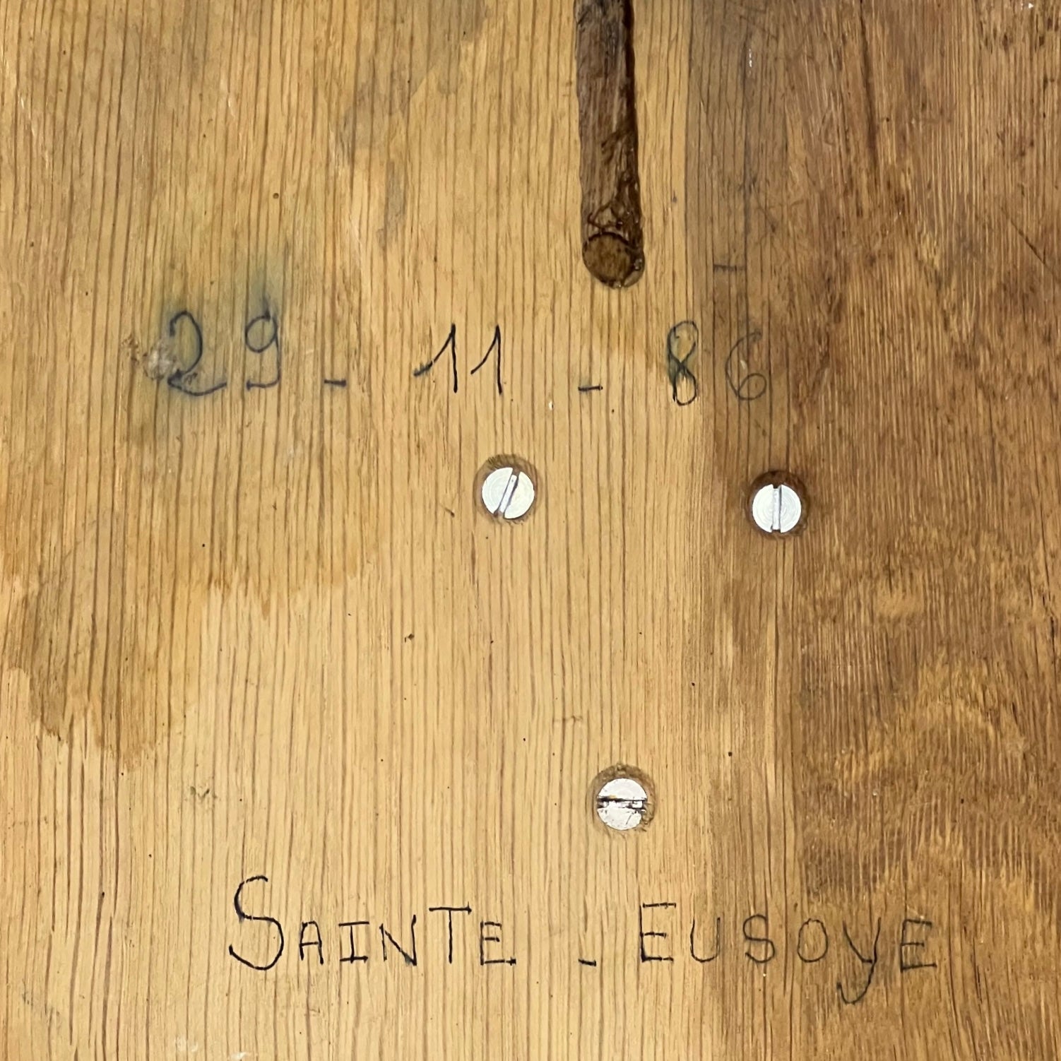 Wooden surface with engraved text and holes, featuring the name 'Sainte Eusoye'.