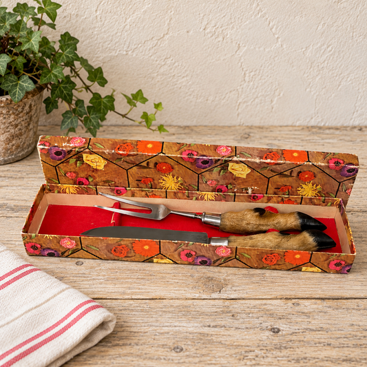 French vintage taxidermy cutlery set with deer hoof handles, displayed in a retro box on a wooden counter with a table cloth and a plant. ideal for a taxidermy collection or hunting gift