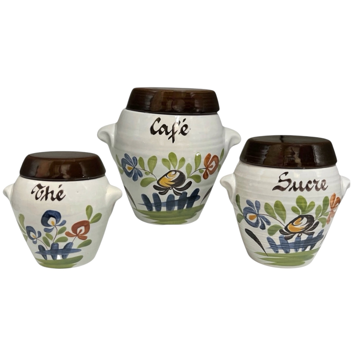 Three white ceramic canisters with dark brown lids, decorated with colorful floral and bee motifs and labeled 'The', 'Cafe', and 'Sucre' on a plain white background.