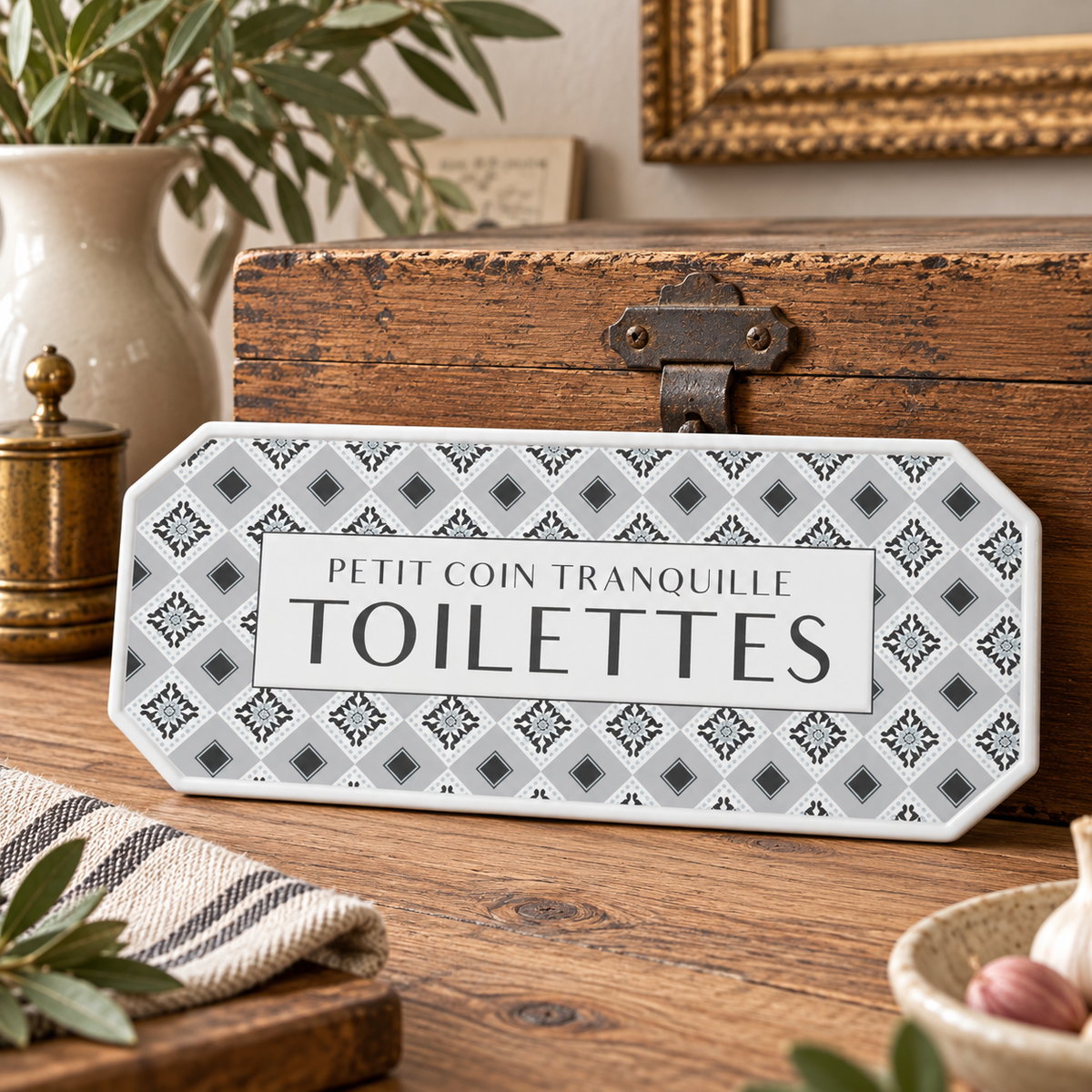 French toilettes sign with a geometric pattern propped against a wooden box on a rustic vignette 
