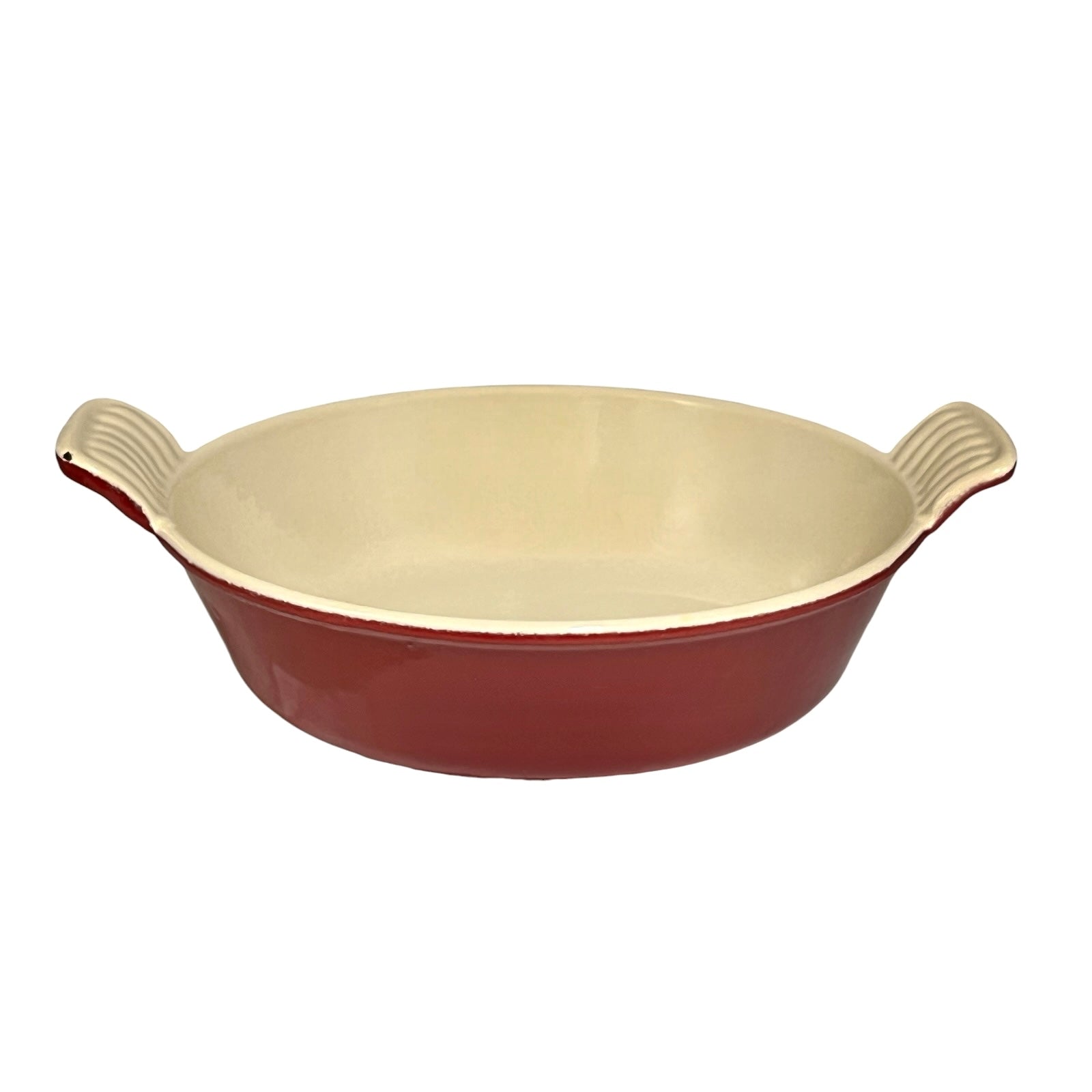 An round ceramic and cast iron baking dish with a glossy dark red exterior and a cream-colored interior, featuring two ribbed side handles.