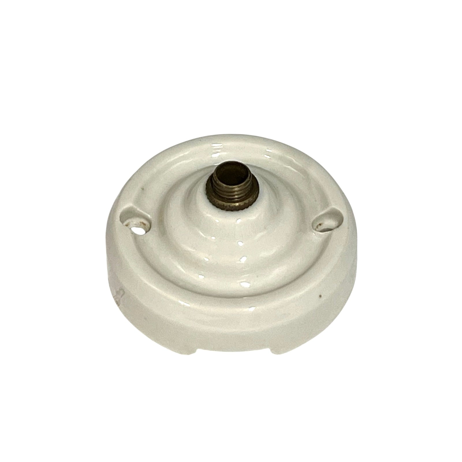 A vintage white porcelain ceiling rose with a brass screw connector on top, isolated on a white background.