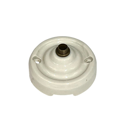 A vintage white porcelain ceiling rose with a brass screw connector on top, isolated on a white background.