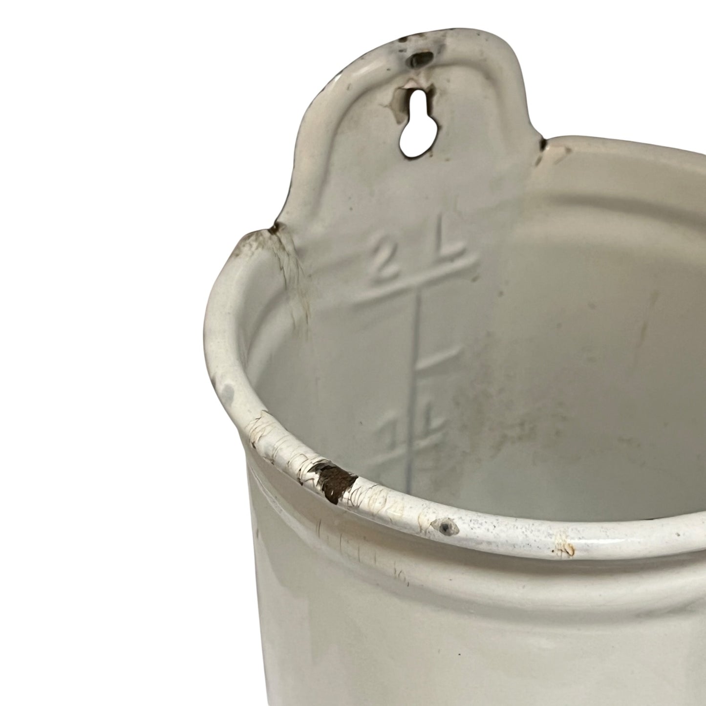 A close-up of a vintage white enamel measuring pitcher with a 2-liter capacity and measurement markings inside, showing some wear and rust on the rim against a white background.