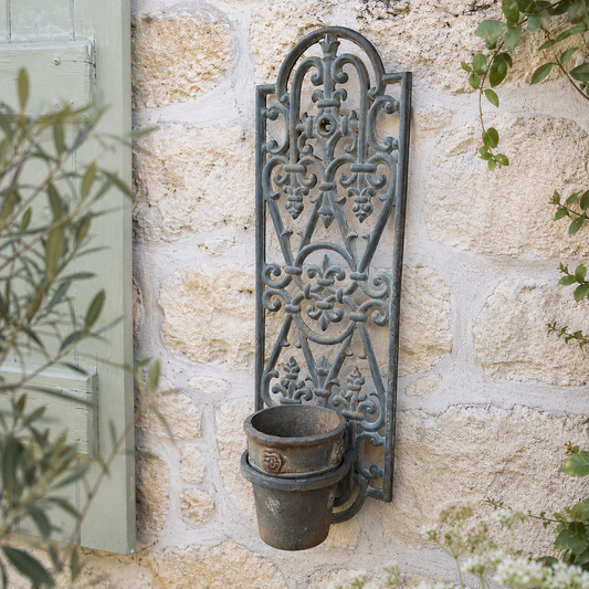 Decorative cast iron French vintage metal wall art with a planter pot on a stone wall