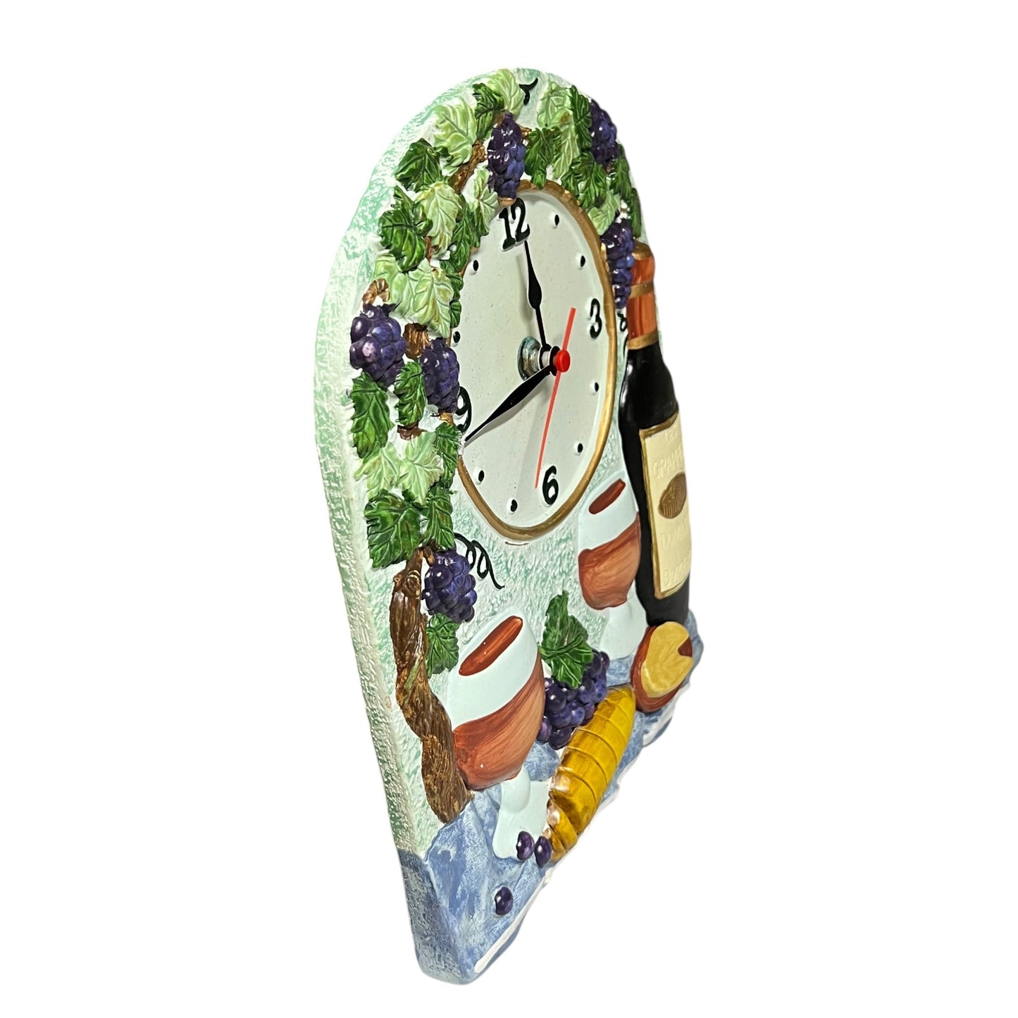 A decorative wall clock shaped like a wine bottle label, featuring a painted grapevine with purple grapes, a white clock face, wine bottles, and small terracotta pots on a plain white background.