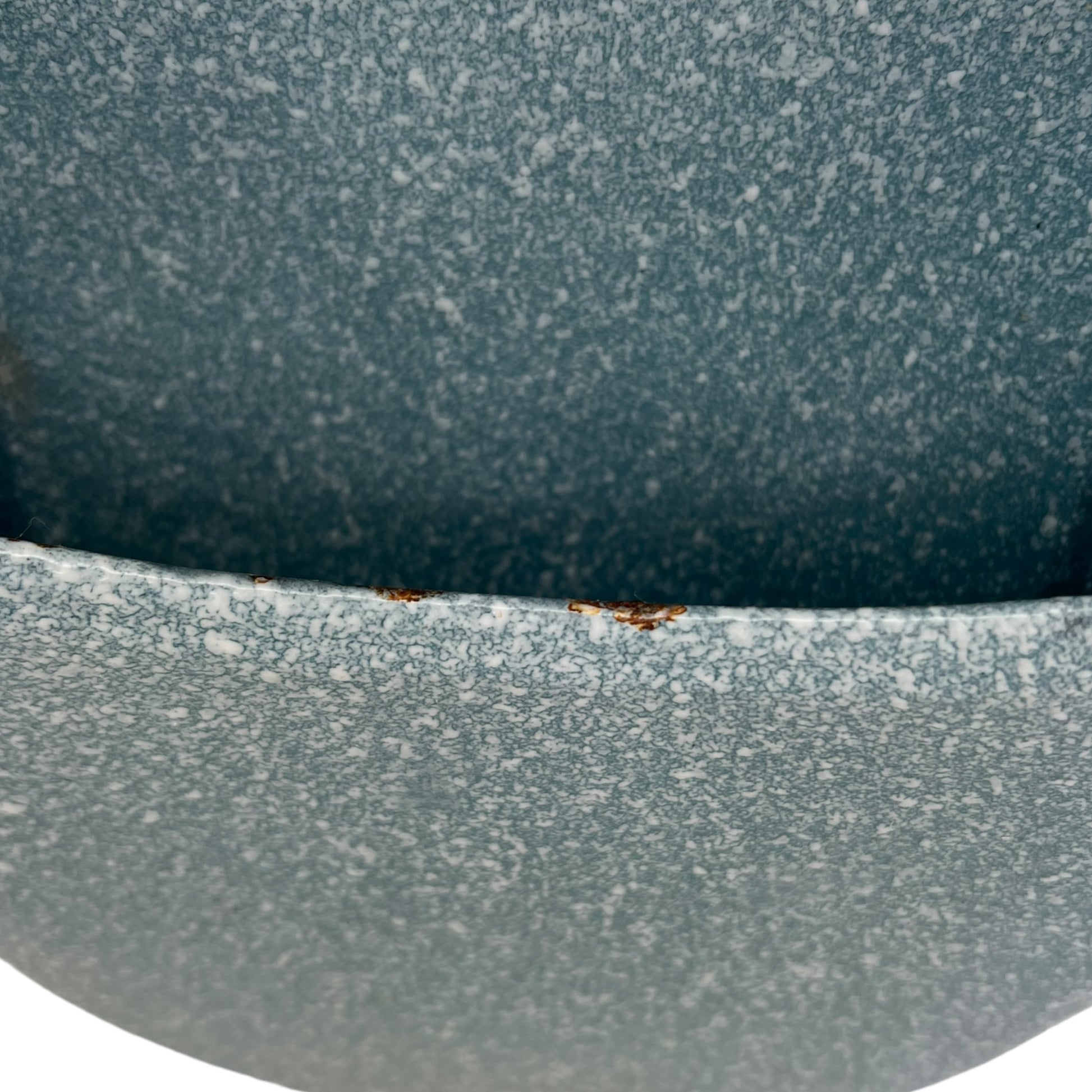 Close-up of wear and tear on a blue metal planter on a white background