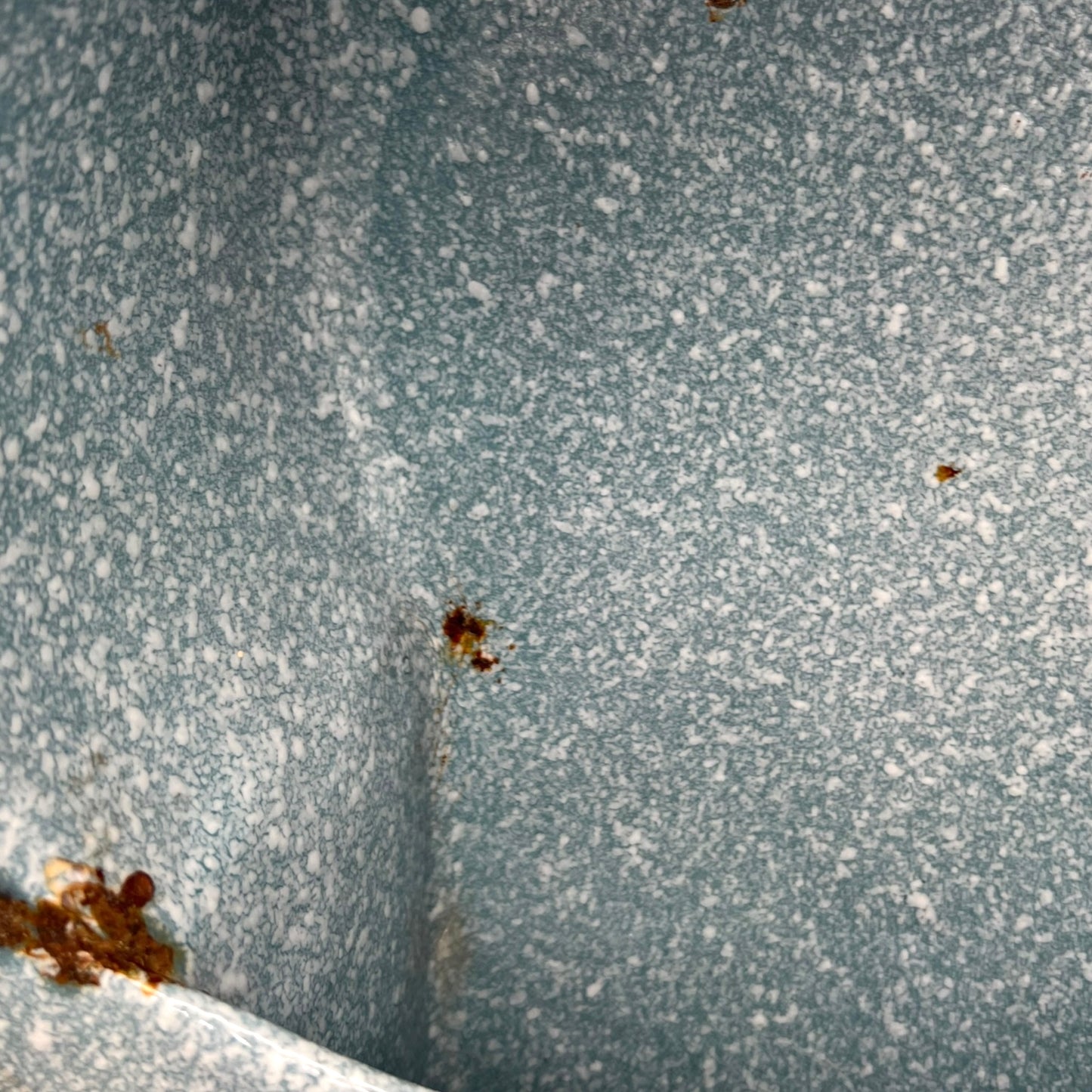 Close-up of wear and tear on a blue metal planter on a white background