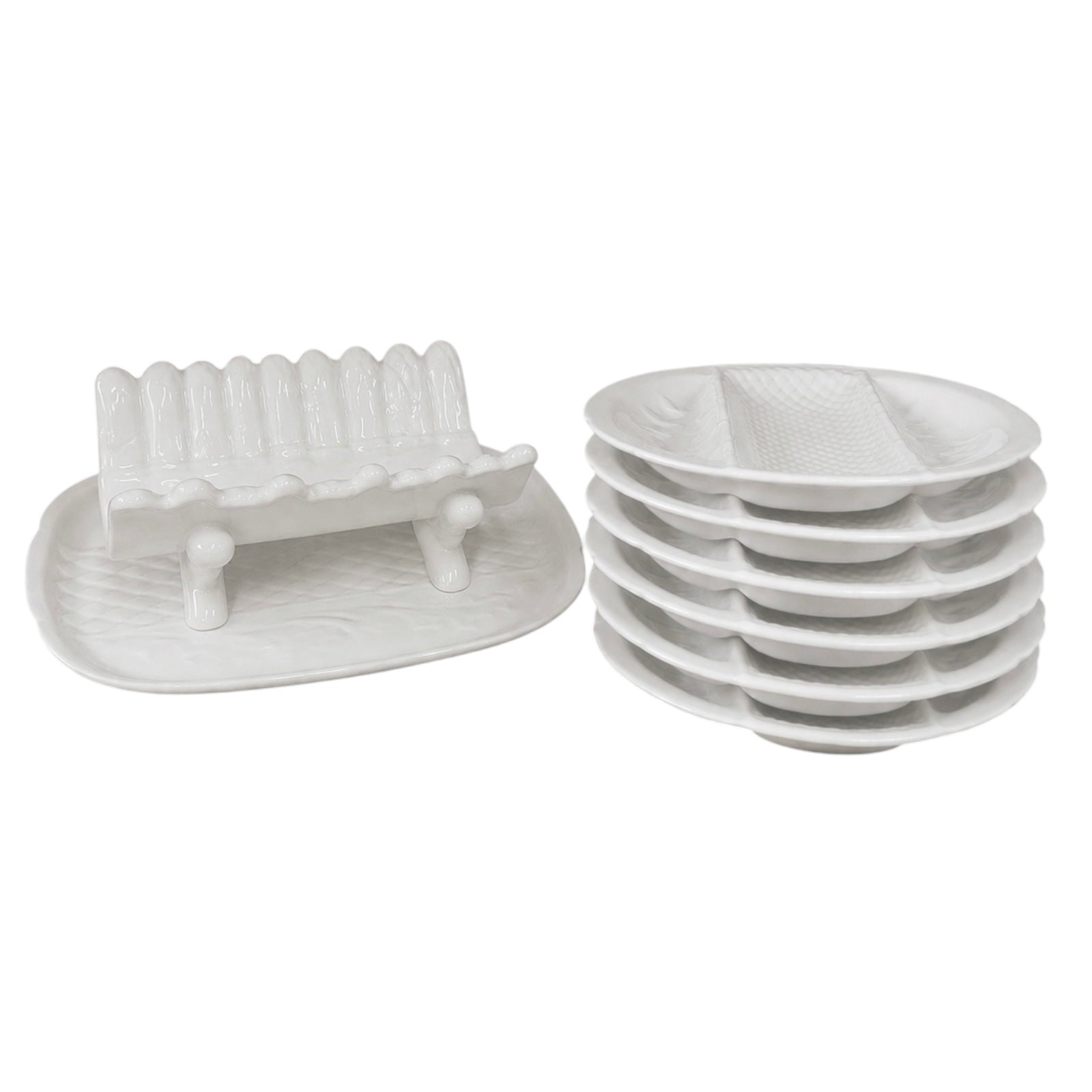 Stacked white ceramic divided serving plates and a matching white ceramic asparagus serving dish displayed on a white background