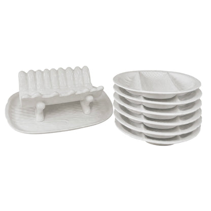 Stacked white ceramic divided serving plates and a matching white ceramic asparagus serving dish displayed on a white background
